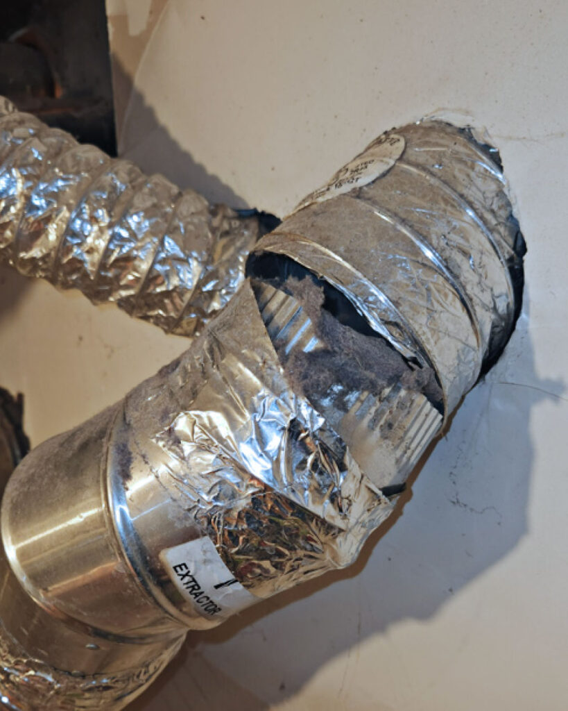 A silver metal dryer vent in disrepair.