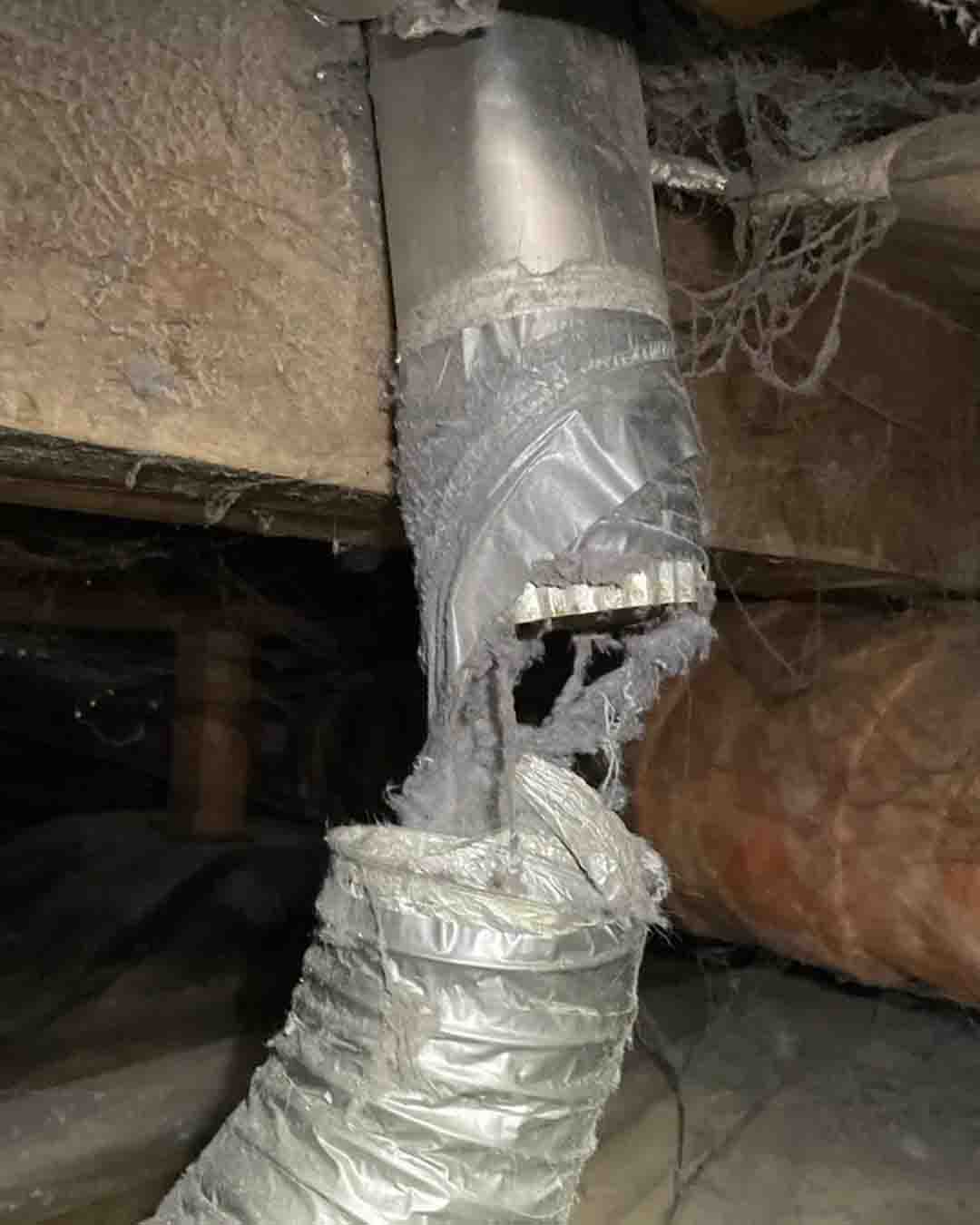 A silver metal dryer vent in disrepair.